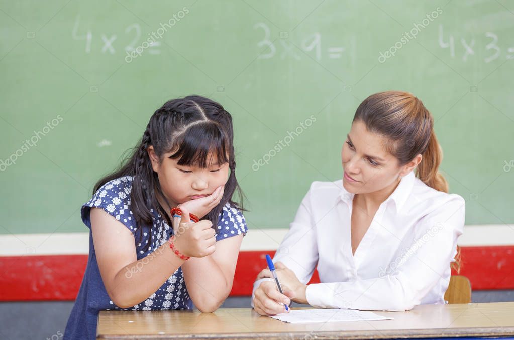 Female teacher with asian child at chalkboard. School concept