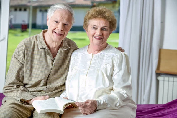 Active elderly couple indoor reading book — Stock Photo, Image