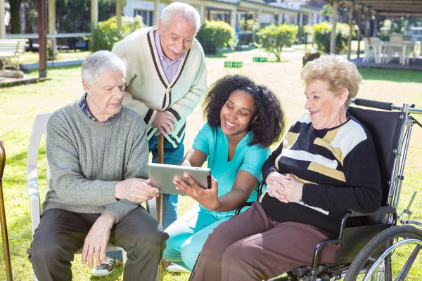 Three active elderly people outdoor reading tablet with african — Stock Photo, Image