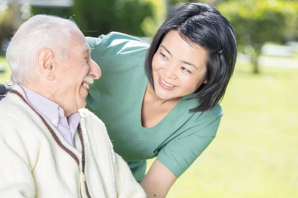 Active elderly retired man outdoor with asian nurse — Stock Photo, Image