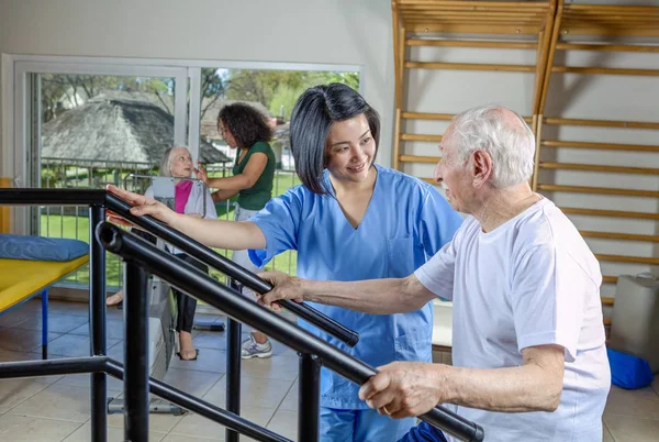 Aktive Senioren im Fitnessstudio mit Hilfe von Krankenschwestern — Stockfoto