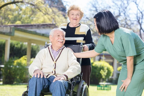 Två aktiva äldre människor utomhus med Asiatiska sjuksköterska — Stockfoto