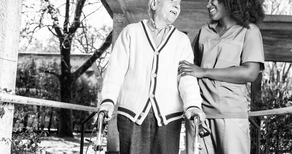Idoso ativo aposentado homem ao ar livre com enfermeira africana — Fotografia de Stock