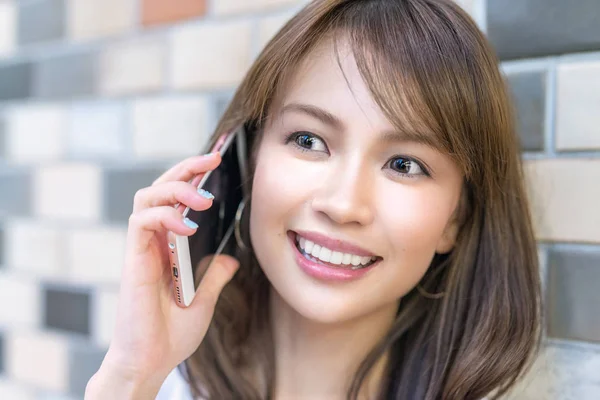 Beautiful asian young girl smiling speaking at the phone — Stock Photo, Image