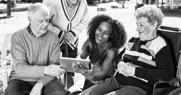 Três idosos ativos ao ar livre leitura tablet com africano — Fotografia de Stock