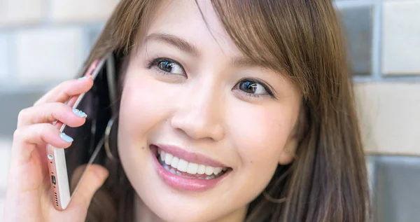 Beautiful asian young girl smiling speaking at the phone — Stock Photo, Image