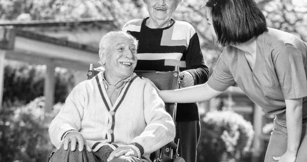 Twee actieve ouderen buiten met Aziatische verpleegkundige — Stockfoto