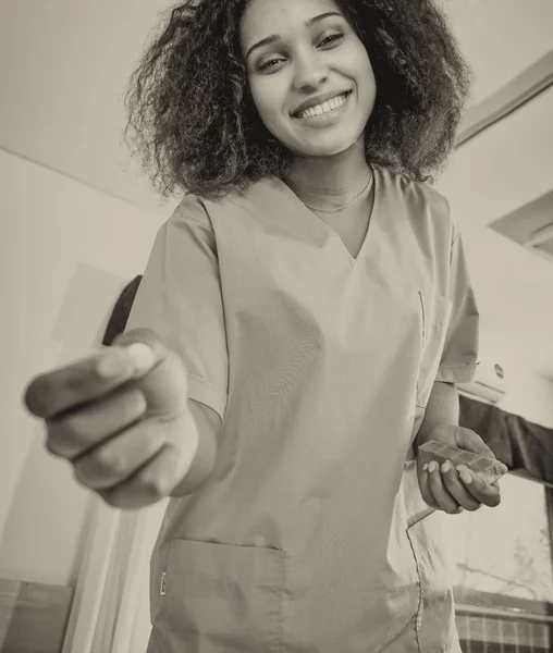 Enfermera africana feliz sonriendo dando píldora al paciente en la cama, upwar —  Fotos de Stock