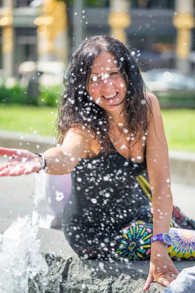 Kobieta gra na wody fontanny w parku miejskim — Zdjęcie stockowe