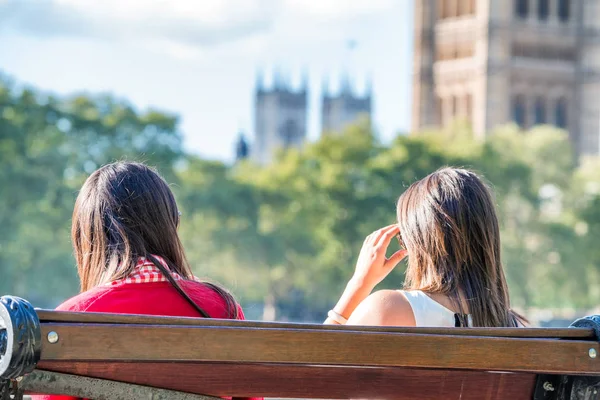 Twee vrouwelijke toeristen op een bankje voor Westminster paleis, L — Stockfoto