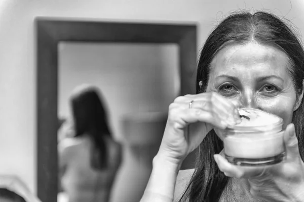 Mulher de 40 anos preparando hidratante em seu rosto. Álcool menina sorridente — Fotografia de Stock