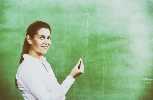 Teacher with chalk at chalkboard — Stock Photo, Image