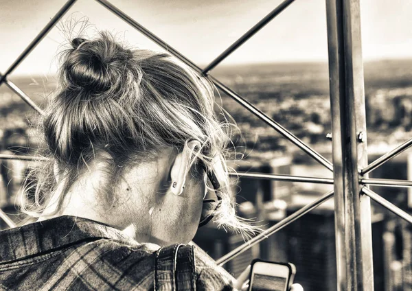 Achteraanzicht van meisje kijken naar mobiele stad foto 's — Stockfoto