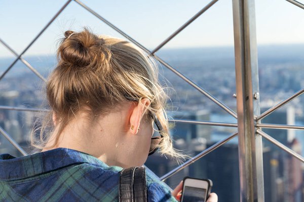 Back view of girl watching mobile city photos.