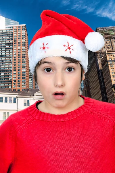 Menino com chapéu de Natal espantado pelo moderno céu da metrópole — Fotografia de Stock