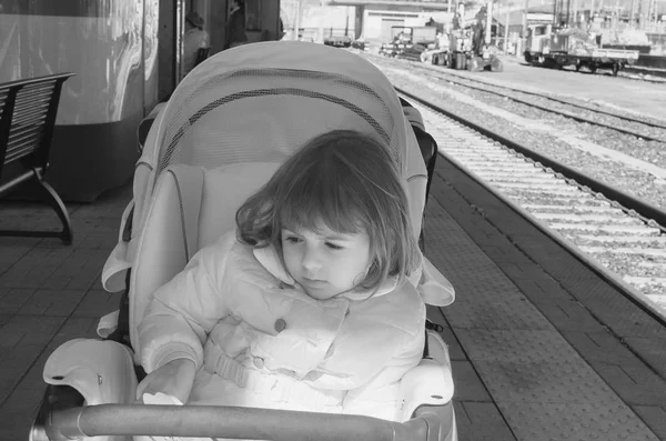 Meisje van de baby in warme jas zitten in moderne wandelwagen in de ligt — Stockfoto