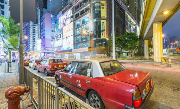 HONG KONG - ABRIL 2014: Taxis rojos a lo largo de las calles de la ciudad por la noche. T — Foto de Stock