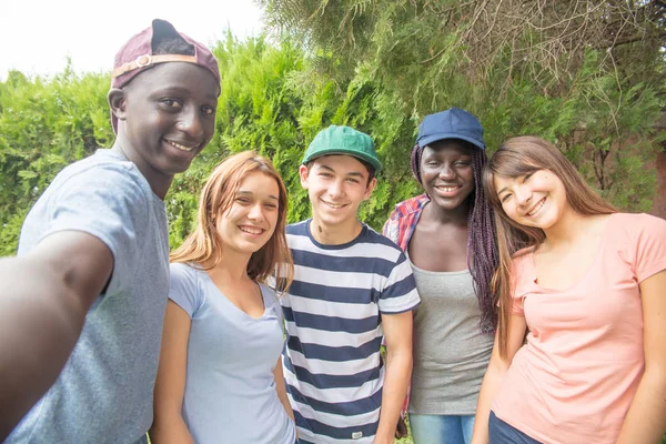 Multi grupo de adolescentes étnicos fazendo selfie se divertindo em um parque — Fotografia de Stock