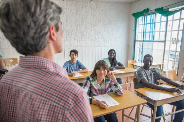 Profesor explicando lección a los alumnos positivos en una t multiétnica — Foto de Stock
