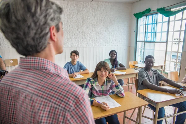 Profesor explicando lección a los alumnos positivos en una t multiétnica —  Fotos de Stock