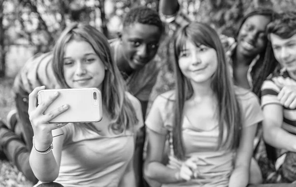 Gruppe multiethnischer Teenager macht Selfie im Sitzen auf dem Rasen — Stockfoto