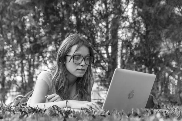青少年使用她的笔记本电脑躺在草地上, 放松和 ed — 图库照片
