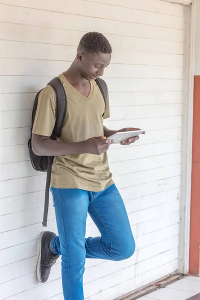 Africano adolescente escolar relajante lectura tableta en hal escuela — Foto de Stock