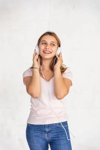 Happy female teenager hearing music with headphones, isolated on