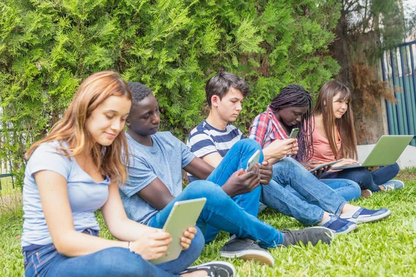 不同种族的青少年使用平板电脑、智能手机和 lapt — 图库照片