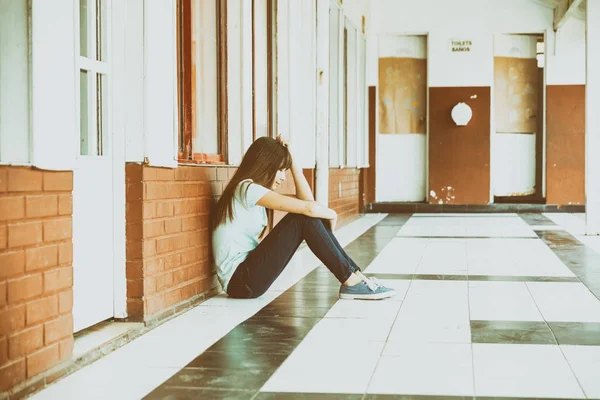 Aislado molesto asiático shoolgirl sentado en la escuela pasillo —  Fotos de Stock
