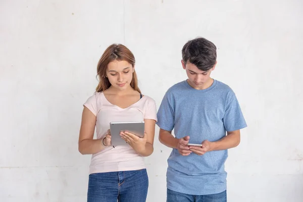 Dois adolescentes brincando com smartphone e tablet, isolados no wh — Fotografia de Stock