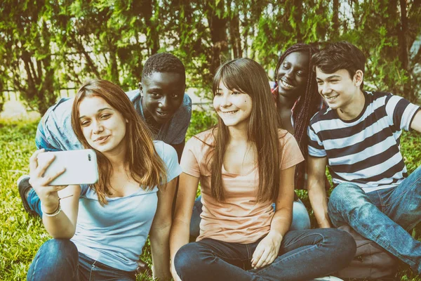 Группа смешанных рас подростки бледнеют со смартфоном на g — стоковое фото