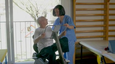 Eğitim ayak üzerinde spor makine içinde jimnastik salonu, ona yardım genç hemşire yaşlı adam 