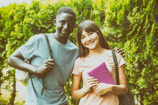 Multi Etniska Tonåringar Par Leende Trädgården Med Sina Ryggsäckar — Stockfoto