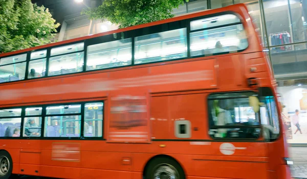 红色公共汽车在城市街道上加速 — 图库照片