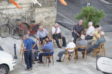 LECCE, ITALY - AĞUSTOS 2012: Yaşlılar kasaba meydanında konuşuyor. Birçok yaşlı insan sıcak mevsimde dışarıda kalır..