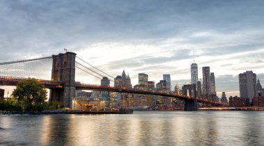 Manhattan siluetinin ve gün batımında, New York'un Brooklyn Bridge Park Brooklyn Köprüsü'nün görünümünden.
