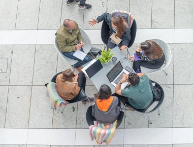 Dizüstü bilgisayarlar, aşağıya doğru görünümü ile bir masada tartışırken işçilerin grup.