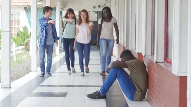 Grupo Adolescentes Caminando Pasillo Escuela Intimidando Niño Sentado Suelo — Vídeos de Stock