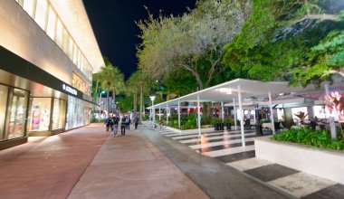 Miami Beach - 25 Şubat 2016: Turist yürüyüş boyunca şehrin sokaklarında gece zaman. Şehir her yıl 25 milyon ziyaretçi çeken.