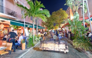 MIAMI - FEBRUARY 25, 2016: Tourists along Espanola Way on a beautiful winter night. Miami Beach is a famous tourist attraction. clipart