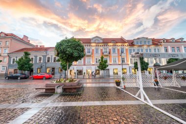VILNIUS, LITHUANIA - JULY 9, 2017: City sunset colors in Town Hall Square. Vilnius attracts 3 million tourists annually. clipart