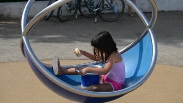 Μικρό Κορίτσι Τρώει Και Απολαμβάνοντας Καρουσέλ Στην Παιδική Χαρά — Αρχείο Βίντεο