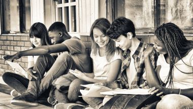 Multi ethnic teenagers friends making school tests outdoor, seated in the school courtyard. clipart