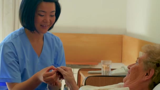 Krankenschwester Spricht Mit Älterer Patientin Die Krankenhaus Bett Liegt — Stockvideo