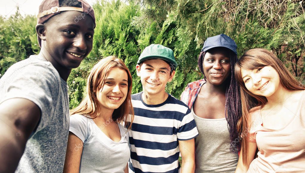 Multi ethnic teenagers smiling outdoor making selfie.