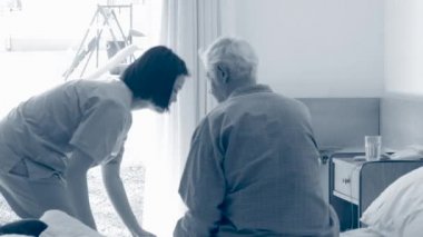 Hemşire yaşlı erkek hasta yatağında yatıyordu için yardım 