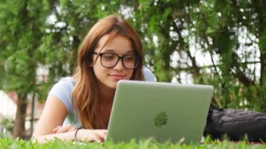 gülümseyen genç kız çim üzerinde yalan tablet PC'yi kullanma 