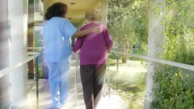 Genç Asyalı kadın doktor hastane bahçesinde koltuk değnekleriyle yaşlı kadına yardım ediyor. Arkadan bak. Arkadan gelen ışık ışınları. Sağlık ve emeklilik kavramı