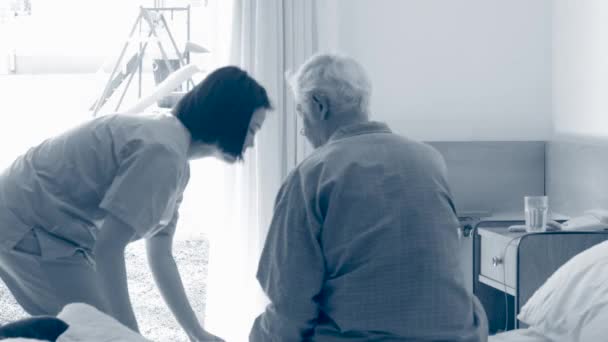 Медсестра Помогает Пожилому Пациенту Лечь Постель — стоковое видео